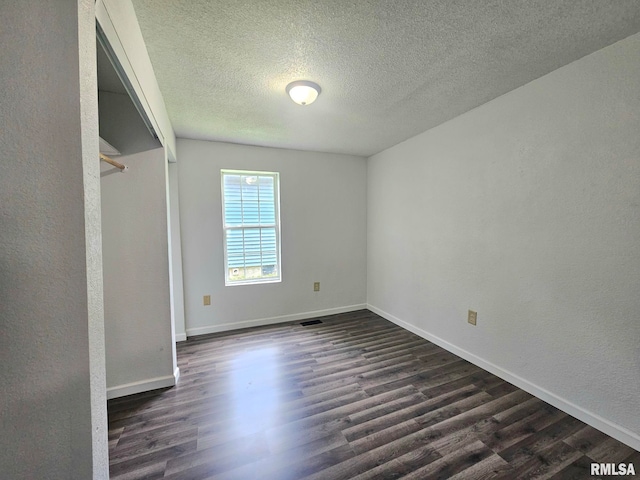 1912 Breese St, Muscatine, IA 52761 - unfurnished bedroom with dark wood-style floors, a textured ceiling, and a textured wall