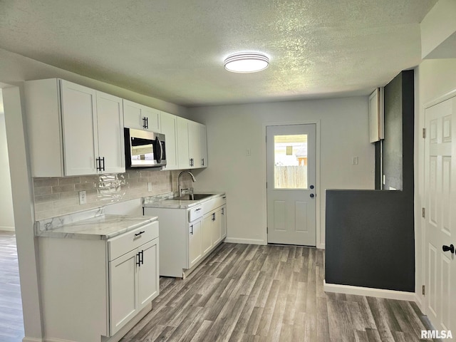 1912 Breese St, Muscatine, IA 52761 - kitchen with stainless steel microwave, light countertops, wood finished floors, a textured ceiling, and decorative backsplash