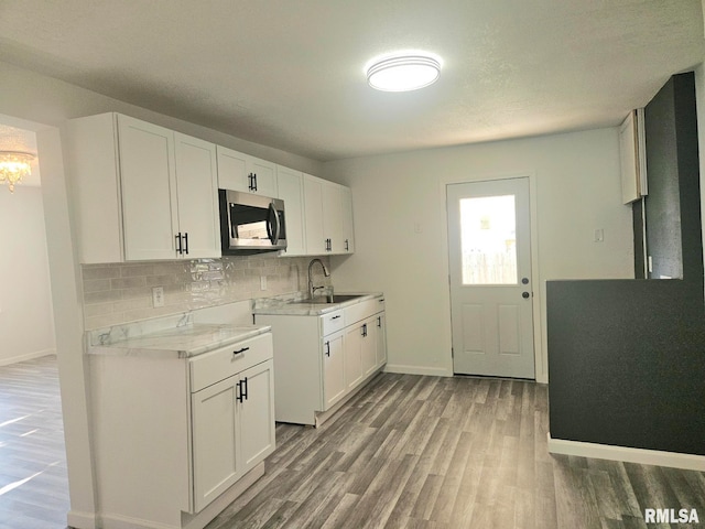 1912 Breese St, Muscatine, IA 52761 - kitchen featuring stainless steel microwave, light wood-style floors, light countertops, tasteful backsplash, and a chandelier