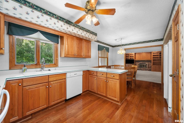 2303 Wynnewood Ct, Davenport, IA 52807 - kitchen featuring white dishwasher, dark wood-type flooring, a peninsula, light countertops, and a textured ceiling