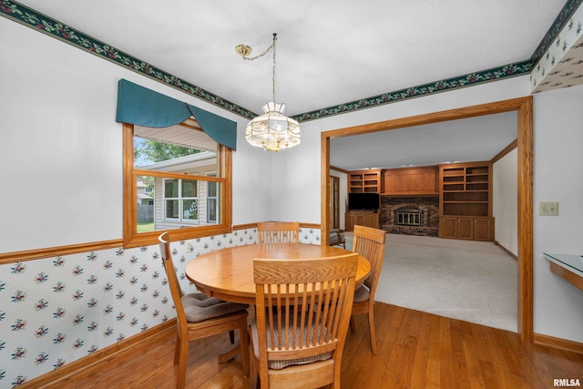 2303 Wynnewood Ct, Davenport, IA 52807 - dining area featuring wood finished floors, a chandelier, wallpapered walls, and a fireplace