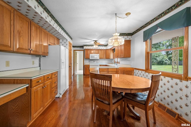 2303 Wynnewood Ct, Davenport, IA 52807 - dining area featuring wood finished floors, wallpapered walls, a ceiling fan, and a textured ceiling
