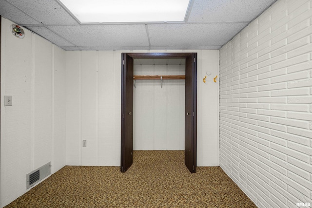 2303 Wynnewood Ct, Davenport, IA 52807 - unfurnished bedroom featuring a paneled ceiling, brick wall, carpet floors, and a closet