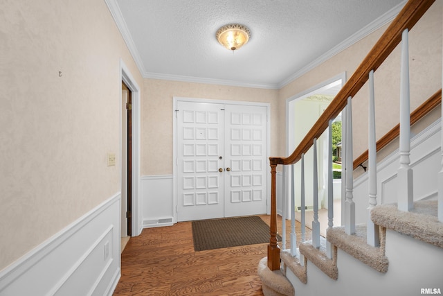 2303 Wynnewood Ct, Davenport, IA 52807 - foyer entrance featuring wood finished floors, a textured ceiling, ornamental molding, stairway, and wainscoting