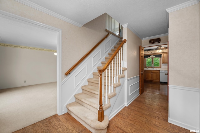 2303 Wynnewood Ct, Davenport, IA 52807 - stairs featuring wood finished floors, ornamental molding, a wainscoted wall, and a textured ceiling