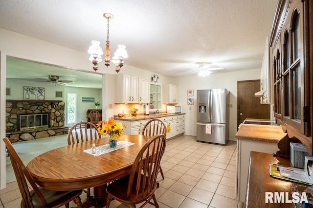 206 Patricia Ln, West Frankfort, IL 62896 - dining room featuring ceiling fan, light tile patterned flooring, a chandelier, a fireplace, and a textured ceiling