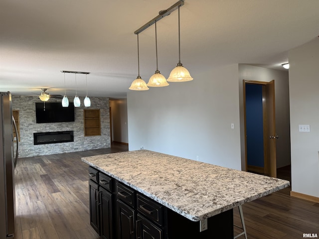 124 Riverview Heights Dr, Le Claire, IA 52753 - kitchen featuring dark cabinets, freestanding refrigerator, dark wood-type flooring, a ceiling fan, and a stone fireplace