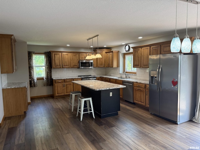 124 Riverview Heights Dr, Le Claire, IA 52753 - kitchen featuring stainless steel appliances, brown cabinetry, a center island, dark wood-type flooring, and recessed lighting