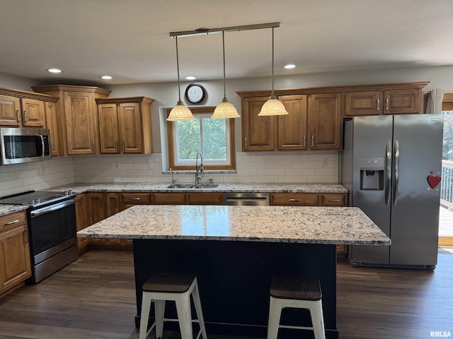 124 Riverview Heights Dr, Le Claire, IA 52753 - kitchen with appliances with stainless steel finishes, a kitchen bar, dark wood finished floors, brown cabinets, and recessed lighting