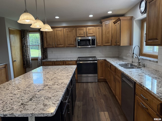 124 Riverview Heights Dr, Le Claire, IA 52753 - kitchen with appliances with stainless steel finishes, dark wood finished floors, a center island, light stone countertops, and decorative backsplash