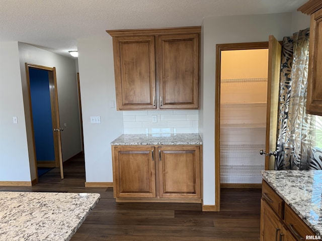 124 Riverview Heights Dr, Le Claire, IA 52753 - kitchen with dark wood finished floors, brown cabinetry, light stone counters, and tasteful backsplash