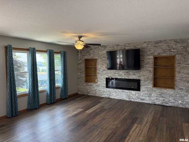 124 Riverview Heights Dr, Le Claire, IA 52753 - unfurnished living room with a textured ceiling, dark wood finished floors, a glass covered fireplace, a ceiling fan, and built in shelves