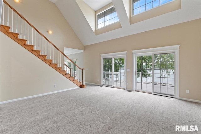 1 S Shore Ln, Rapids City, IL 61278 - unfurnished living room featuring a towering ceiling, plenty of natural light, stairway, and carpet flooring