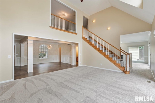 1 S Shore Ln, Rapids City, IL 61278 - unfurnished living room with carpet flooring, ornate columns, high vaulted ceiling, stairs, and a chandelier