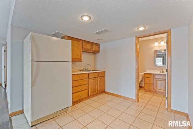 1 S Shore Ln, Rapids City, IL 61278 - kitchen with freestanding refrigerator, light countertops, brown cabinetry, and a textured ceiling