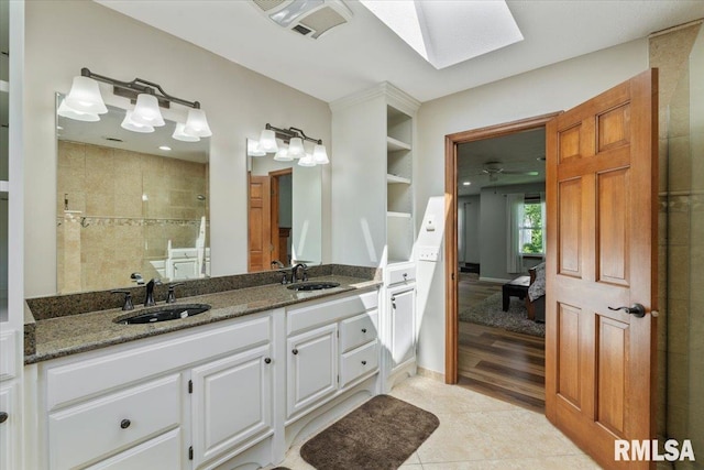 6470 James Rd, Bettendorf, IA 52722 - bathroom featuring a skylight, double vanity, connected bathroom, a tile shower, and tile patterned floors