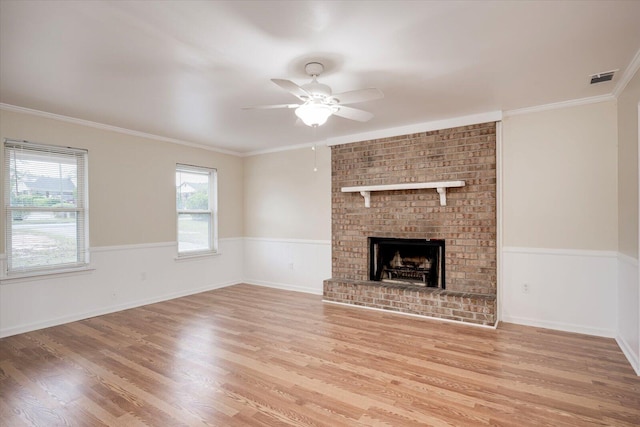 unfurnished living room featuring ceiling fan, light wood-type flooring, ornamental molding, and a fireplace