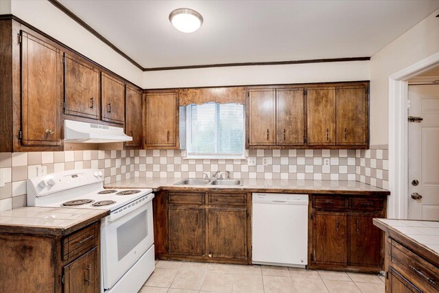 kitchen with white appliances, backsplash, crown molding, sink, and light tile patterned floors