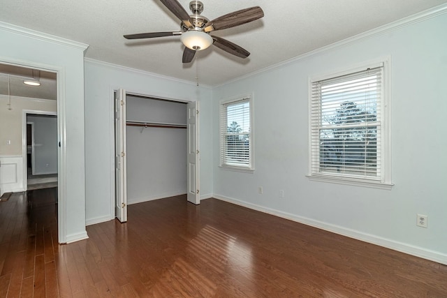 unfurnished bedroom featuring ceiling fan, a closet, dark wood-type flooring, and ornamental molding