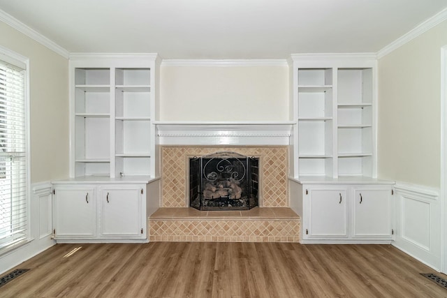 unfurnished living room with plenty of natural light, ornamental molding, and a tiled fireplace