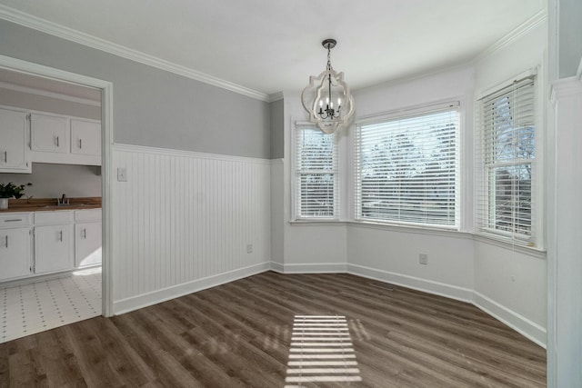 unfurnished dining area featuring an inviting chandelier, dark hardwood / wood-style flooring, crown molding, and sink