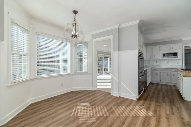 unfurnished dining area featuring dark hardwood / wood-style floors, ornamental molding, and a notable chandelier