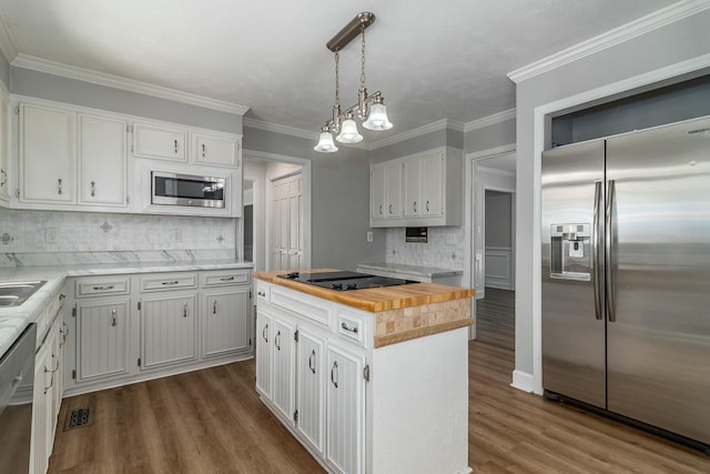 kitchen with appliances with stainless steel finishes, tasteful backsplash, a kitchen island, pendant lighting, and white cabinets