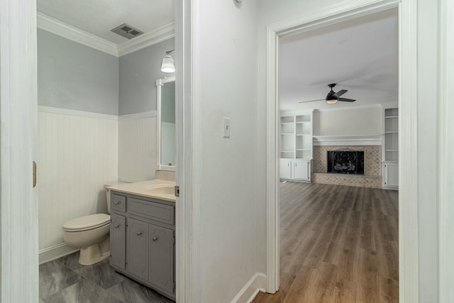 bathroom featuring ceiling fan, vanity, toilet, crown molding, and built in features