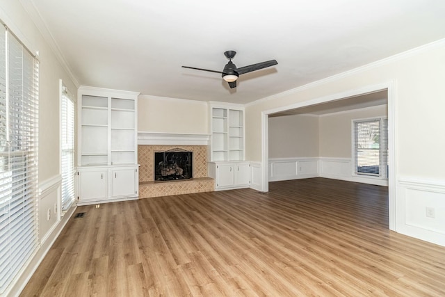 unfurnished living room featuring ceiling fan, a wealth of natural light, crown molding, and built in features