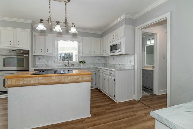 kitchen with stainless steel appliances, hanging light fixtures, a kitchen island, white cabinets, and sink