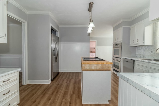 kitchen featuring decorative light fixtures, wooden counters, a kitchen island, stainless steel appliances, and white cabinets