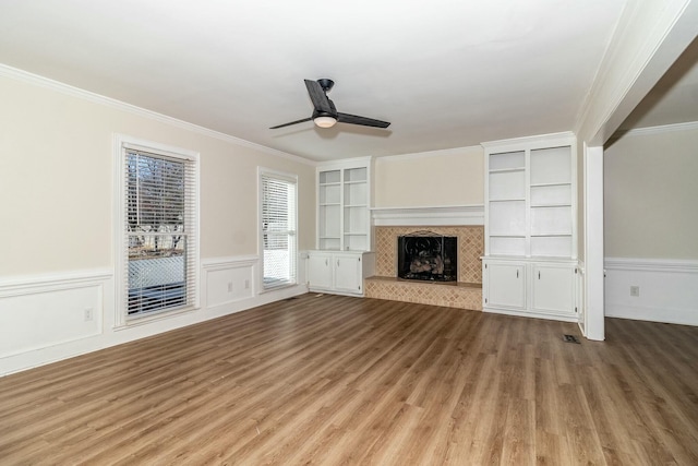 unfurnished living room with ceiling fan, light wood-type flooring, built in features, and ornamental molding