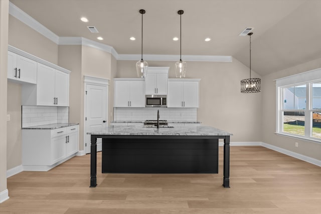 kitchen featuring white cabinetry, a notable chandelier, and stainless steel microwave