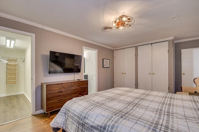 bedroom featuring ornamental molding, baseboards, light wood finished floors, visible vents, and a closet