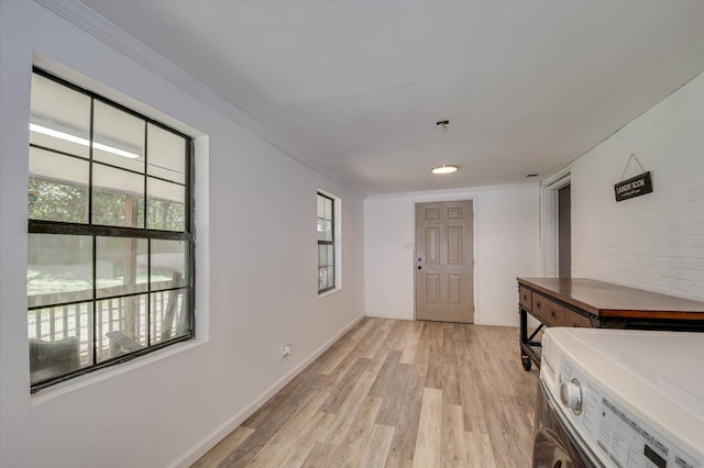 hall featuring light wood finished floors, baseboards, separate washer and dryer, and crown molding