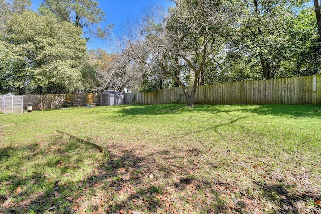 view of yard featuring a fenced backyard, an outbuilding, and a storage shed