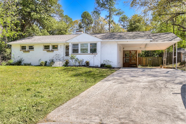 single story home with a chimney, concrete driveway, a front yard, brick siding, and a carport