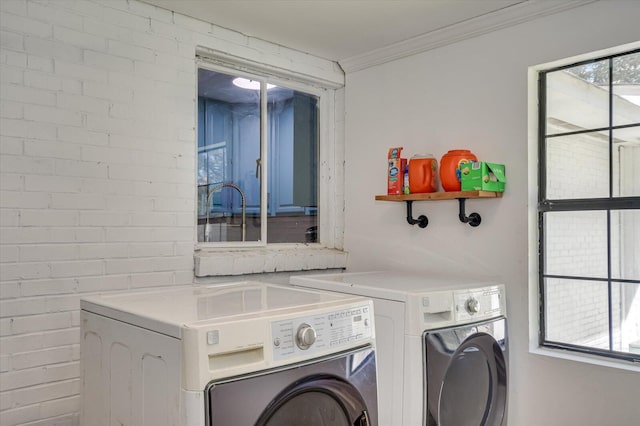 clothes washing area with washing machine and dryer, ornamental molding, and a healthy amount of sunlight