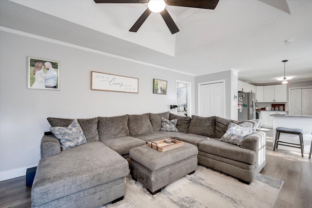 living room with crown molding, ceiling fan, light hardwood / wood-style floors, and a tray ceiling