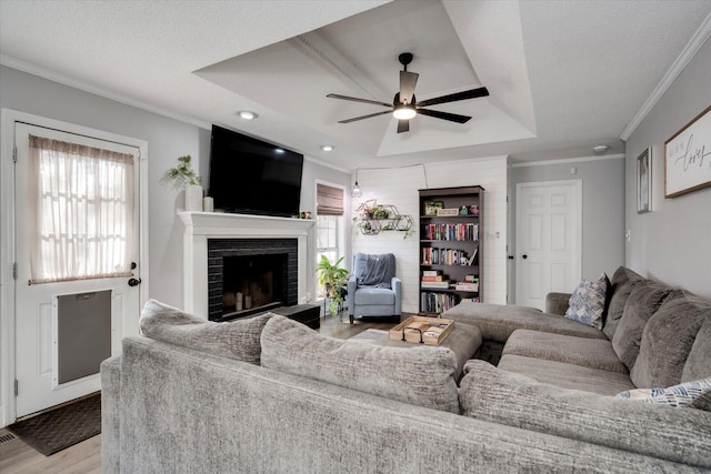 living room with a fireplace, a tray ceiling, light hardwood / wood-style flooring, and a textured ceiling