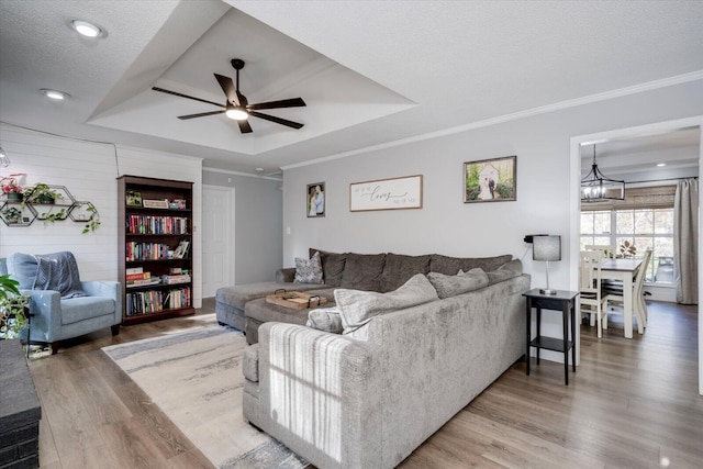 living room with hardwood / wood-style floors, a tray ceiling, ornamental molding, and a textured ceiling