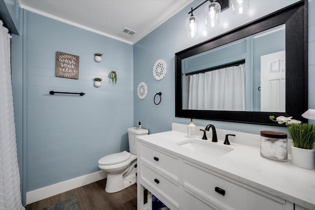 bathroom with toilet, a textured ceiling, ornamental molding, vanity, and hardwood / wood-style flooring