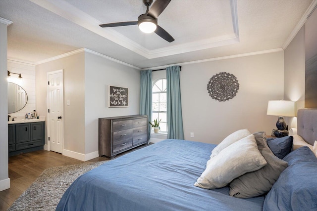 bedroom with ensuite bath, ornamental molding, dark hardwood / wood-style floors, a raised ceiling, and ceiling fan