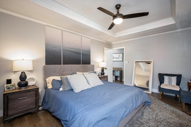 bedroom featuring dark hardwood / wood-style flooring, crown molding, ceiling fan, and a tray ceiling