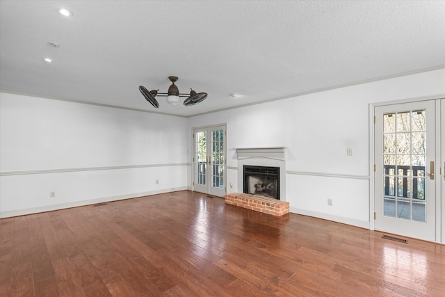 unfurnished living room featuring a brick fireplace, french doors, visible vents, and wood finished floors