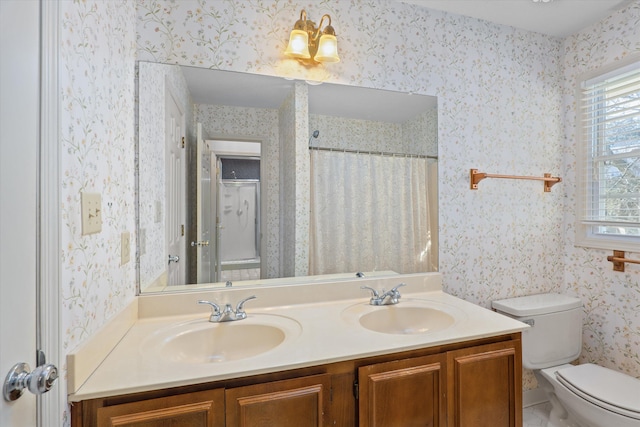 full bath featuring toilet, wallpapered walls, double vanity, and a sink