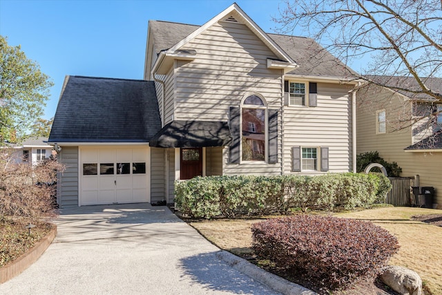 traditional home with concrete driveway, roof with shingles, and an attached garage