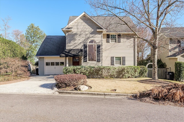 traditional home with driveway, an attached garage, and a shingled roof