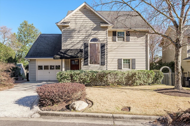 traditional-style house featuring an attached garage, a shingled roof, fence, and concrete driveway