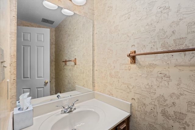 bathroom featuring wallpapered walls, visible vents, vaulted ceiling, and vanity